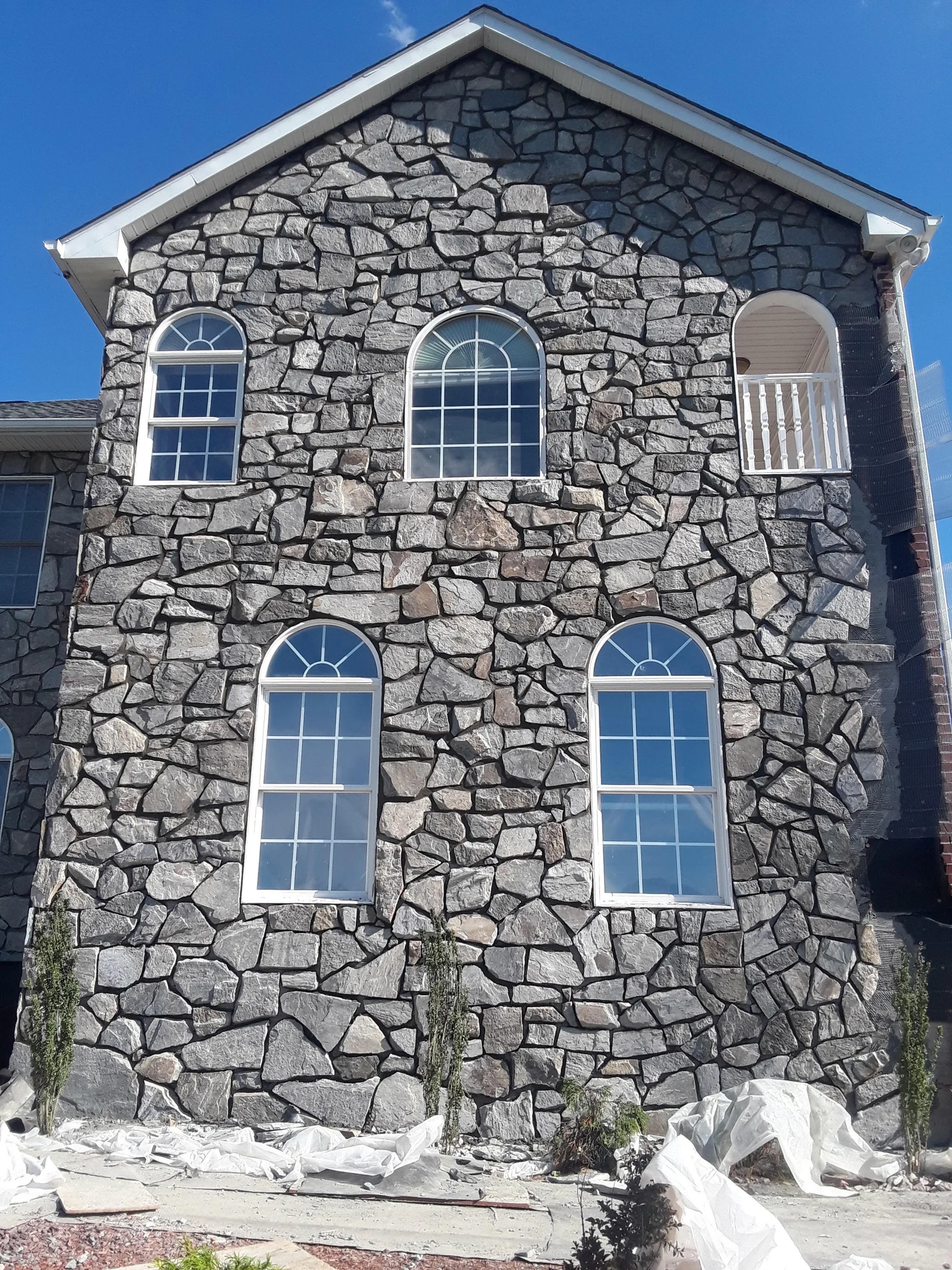 Stone-clad house front with arched window