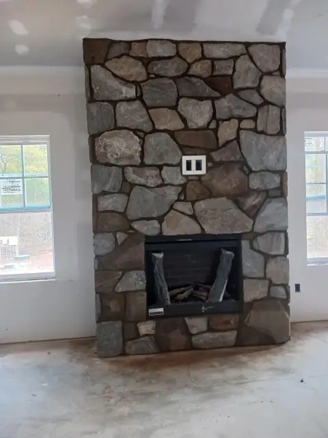 Completed indoor stone fireplace with black stove insert