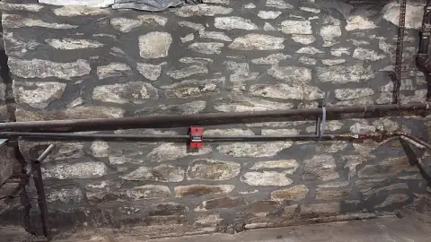 Repointed natural stone basement wall around utility lines