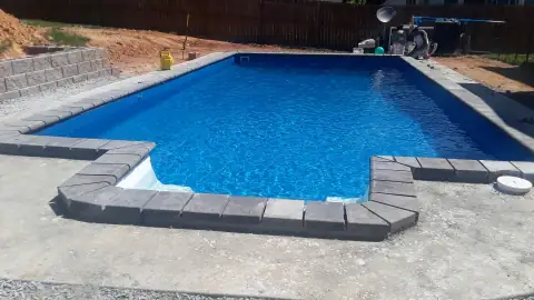 Completed dark stone pool coping around a backyard pool