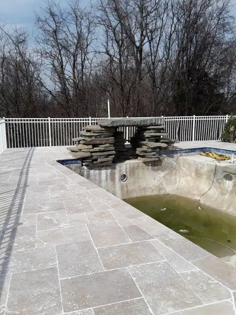 Stone pool deck renovation around an empty pool