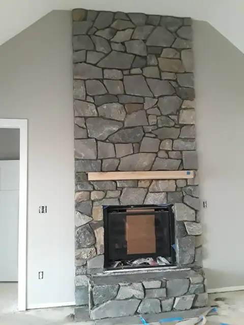 Indoor natural stone fireplace installation before completion