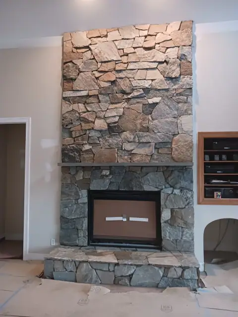 Finished rustic stone fireplace with wood mantel