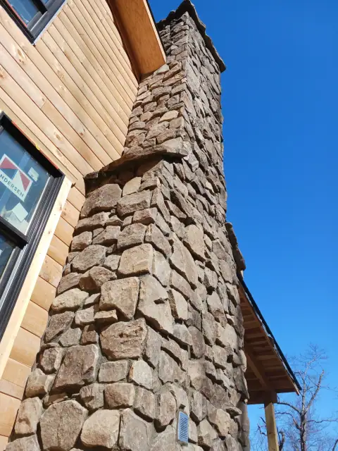 Completed natural stone chimney on a timber home
